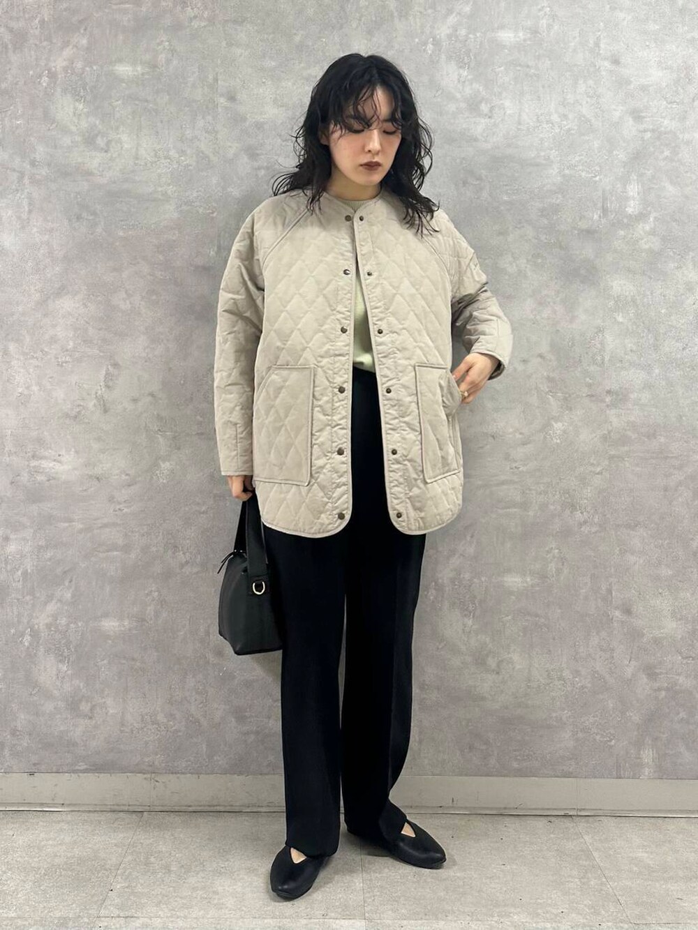 グリーン系のニット/セーター、ブラック系のパンプス、グレー系のダウンジャケット/コートを着用したレディースの冬コーディネートの5枚目の写真