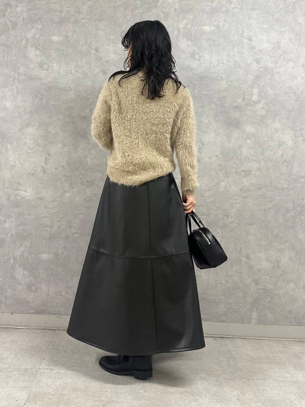 ブラック系のその他アウター、ブラック系のショルダーバッグ、ブラック系のスカートを着用したレディースの冬コーディネートの3枚目の写真