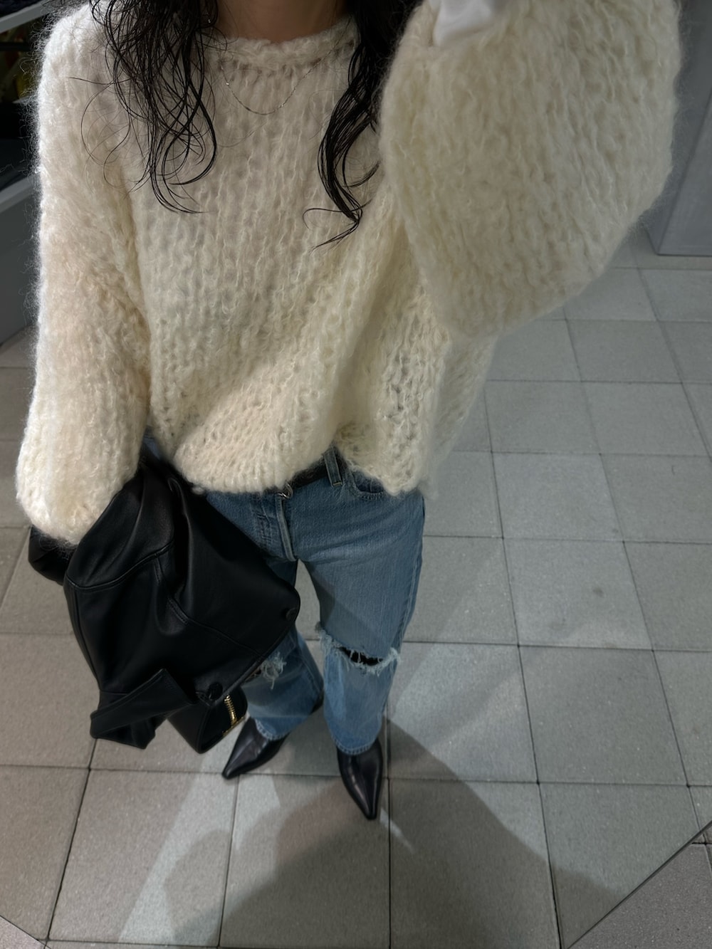 ブルー系のデニムパンツ、ホワイト系のニット/セーター、ブラック系のブーツを着用したレディースの秋コーディネートの3枚目の写真