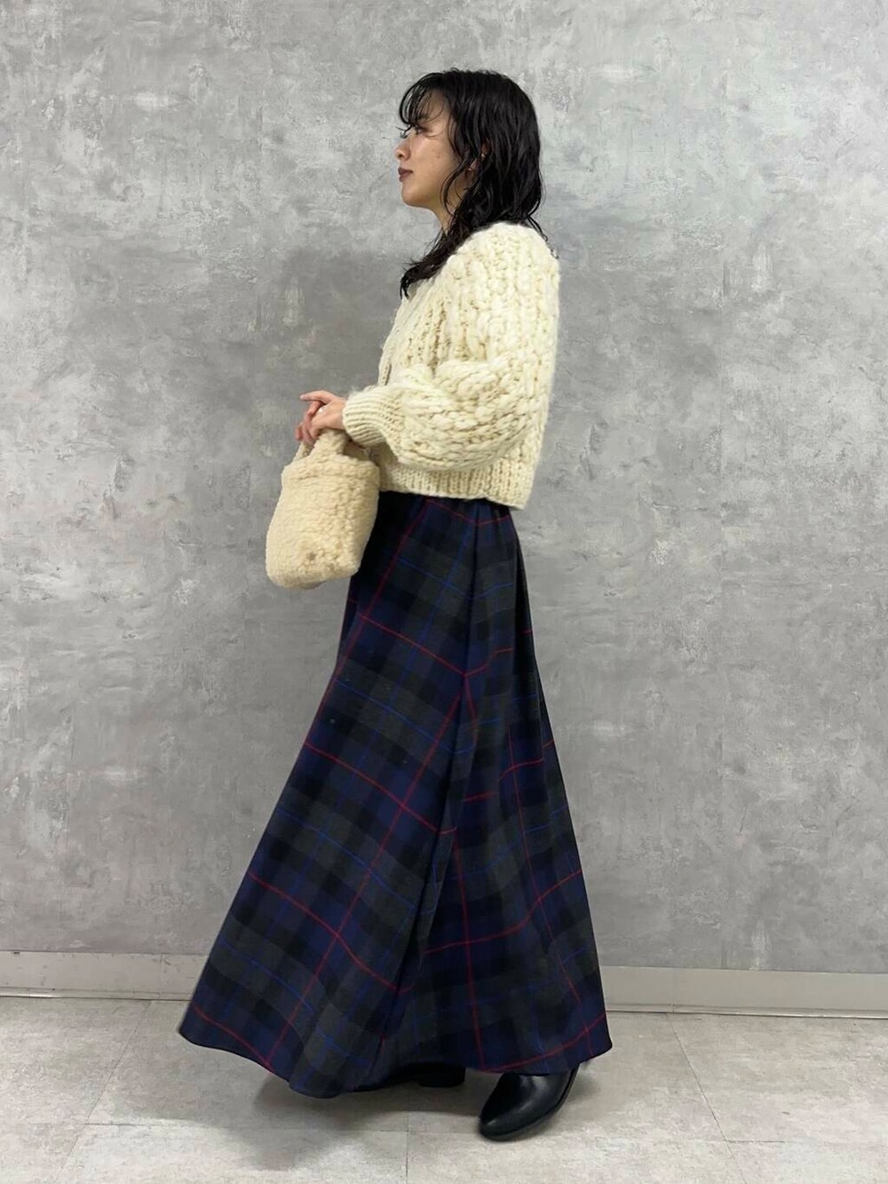 ホワイト系のカーディガン/ボレロ、ブラック系のブーツ、ブルー系のスカートを着用したレディースの冬コーディネートの2枚目の写真