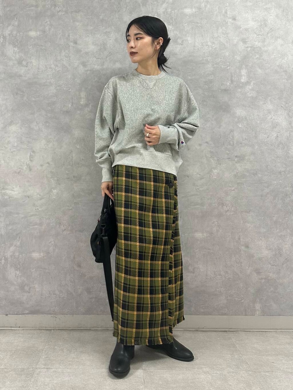 ブラック系のショルダーバッグ、グリーン系のスカート、グレー系のTシャツ/カットソーを着用したレディースの秋コーディネートの4枚目の写真