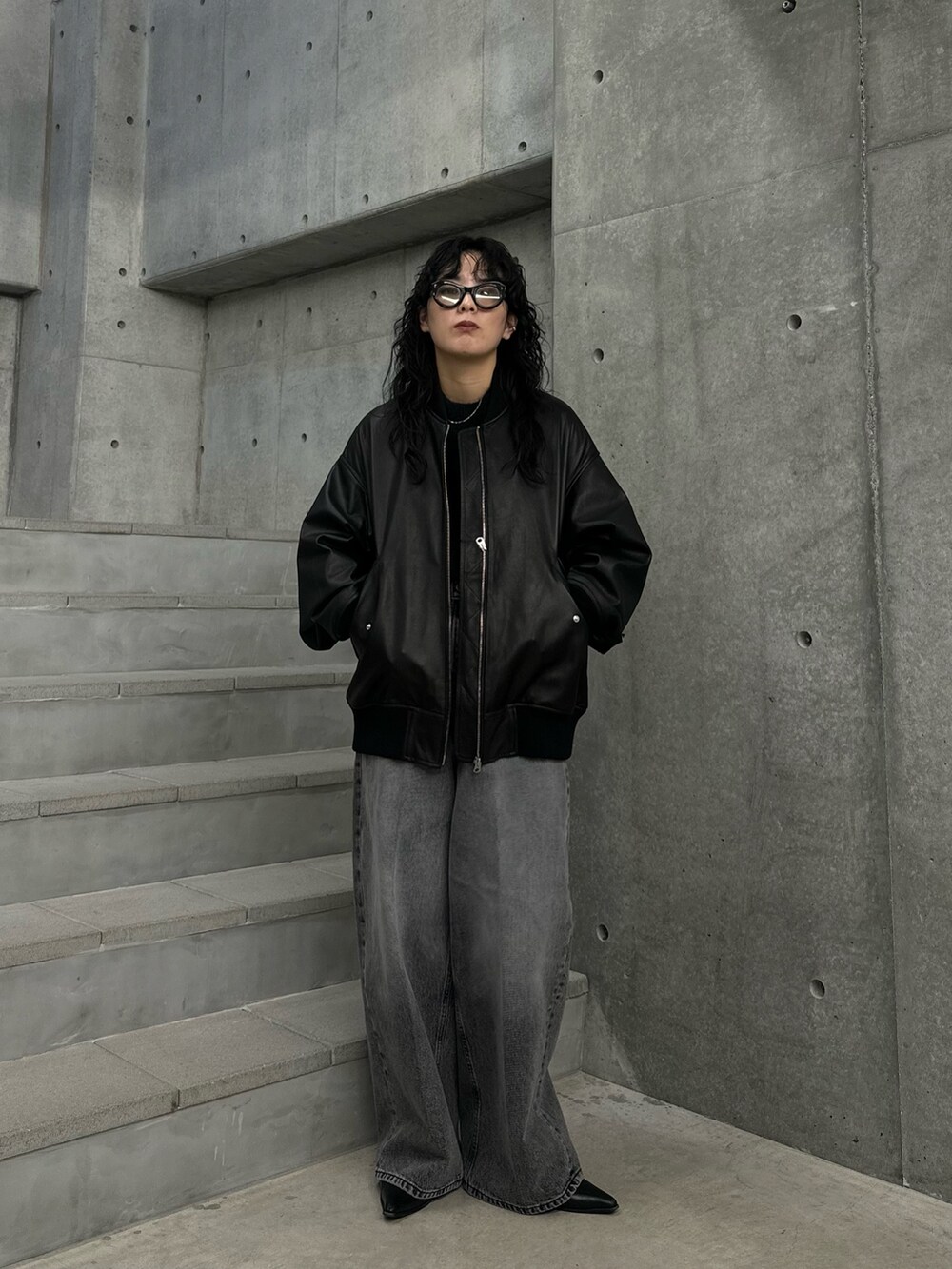 ブラック系のニット/セーター、グレー系のデニムパンツ、ブラック系のブーツを着用したレディースの秋コーディネートの4枚目の写真