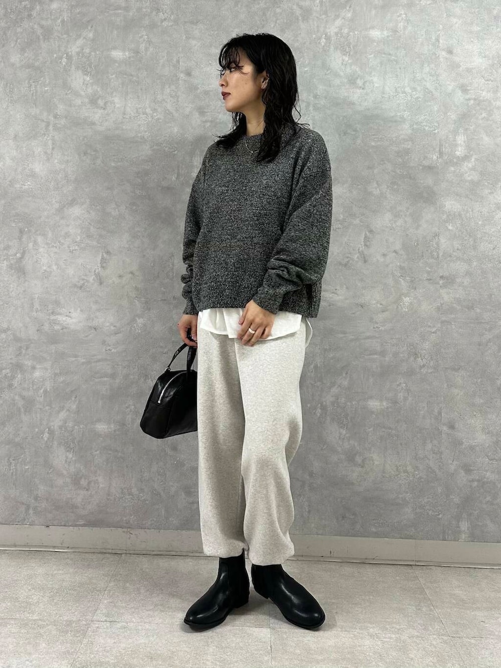 ブラック系のショルダーバッグ、ブラック系のブーツ、ホワイト系のTシャツ/カットソーを着用したレディースの冬コーディネートの5枚目の写真