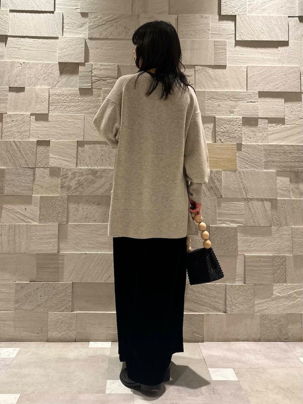 ブラック系のスカート、グレー系のニット/セーター、ブラック系のハンドバッグを着用したレディースの冬コーディネートの3枚目の写真