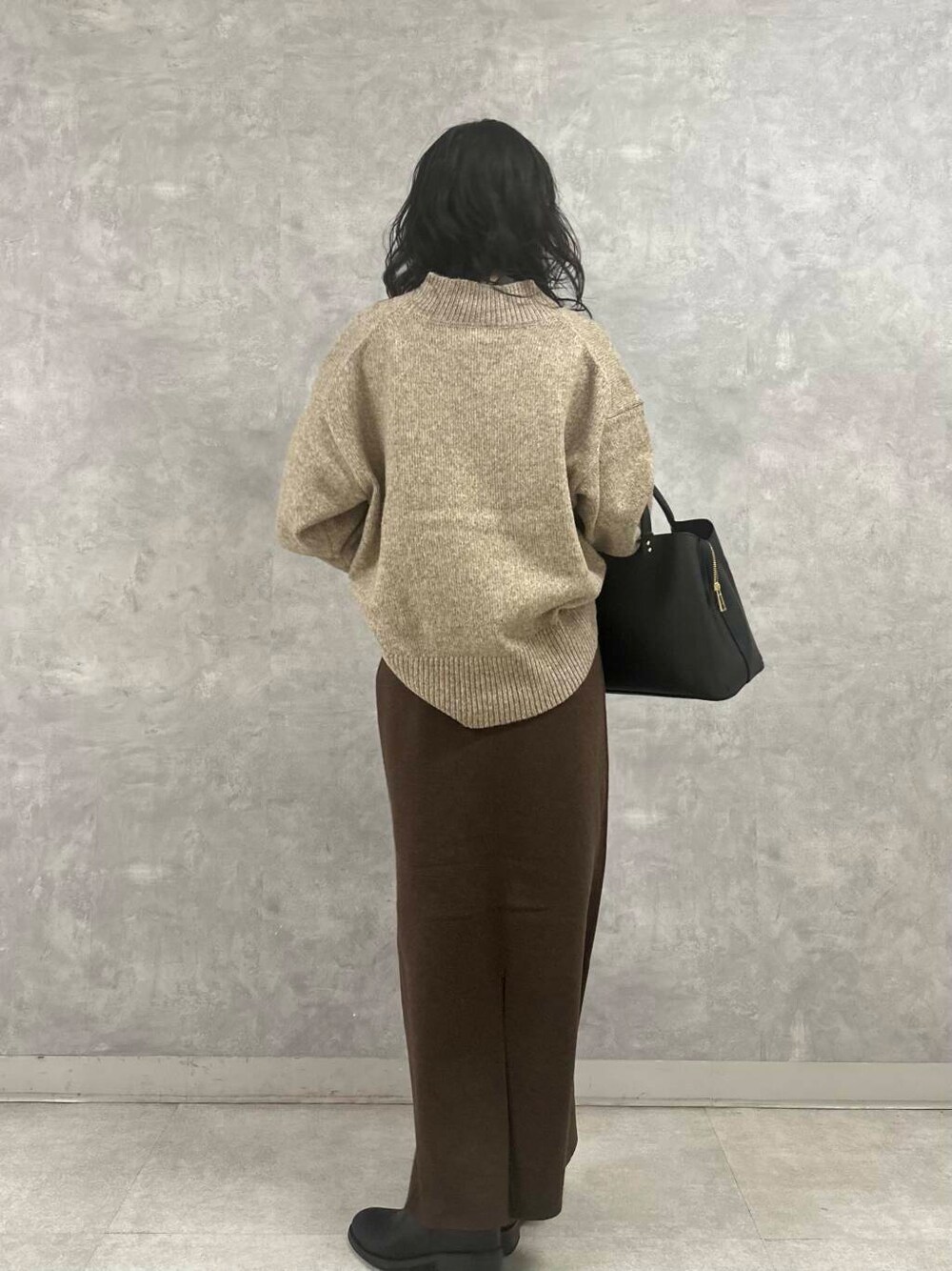 ブラウン系のスカート、ベージュ系のニット/セーター、ブラック系のトートバッグを着用したレディースの冬コーディネートの4枚目の写真