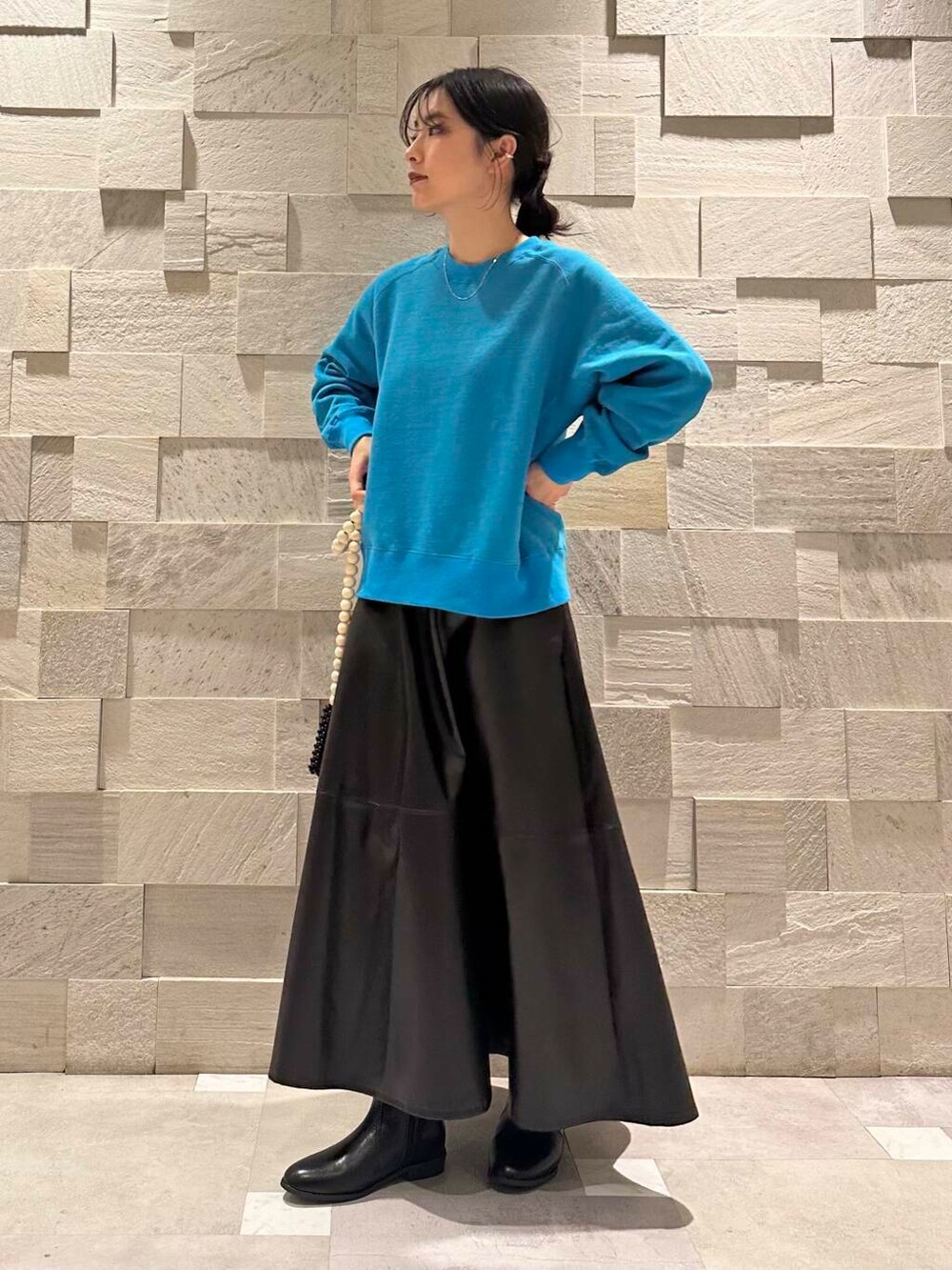 ブルー系のスウェット、ブラック系のブーツ、ブラック系のスカートを着用したレディースの秋コーディネートの2枚目の写真