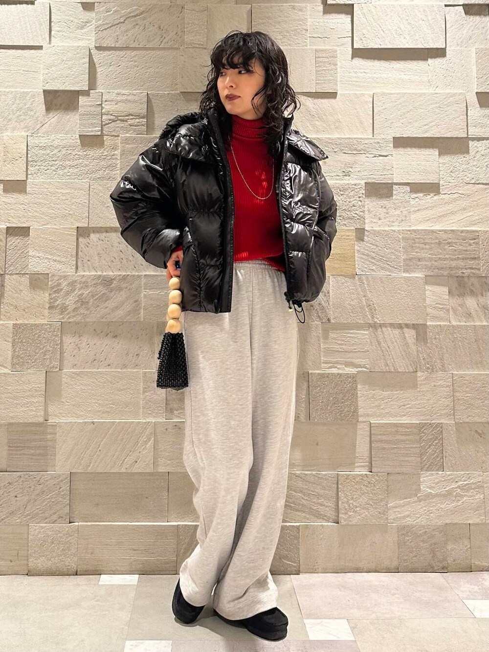 レッド系のニット/セーター、グレー系のその他パンツ、ブラック系のダウンジャケット/コートを着用したレディースの冬コーディネートの2枚目の写真