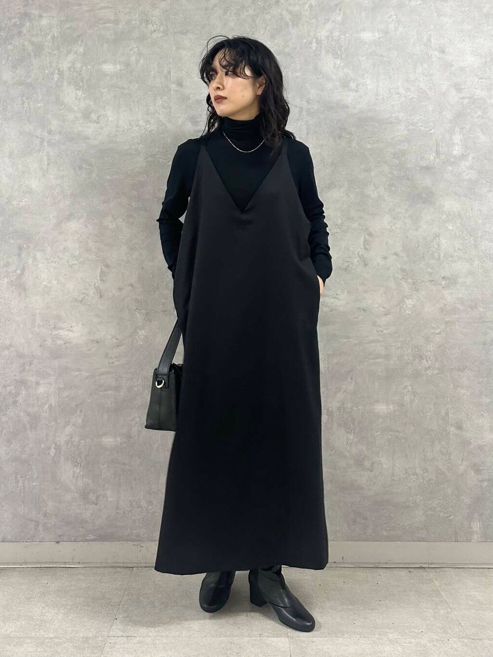 ブラック系のブーツ、ブラック系のTシャツ/カットソー、ブラック系のショルダーバッグを着用したレディースの冬コーディネートの2枚目の写真