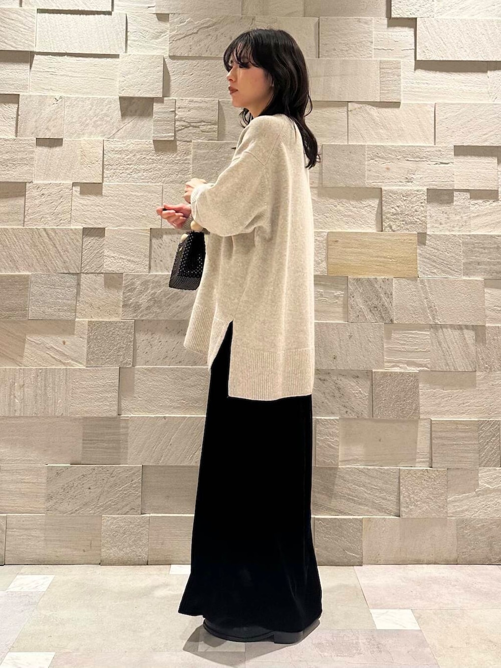 ブラック系のスカート、グレー系のニット/セーター、ブラック系のハンドバッグを着用したレディースの冬コーディネートの2枚目の写真