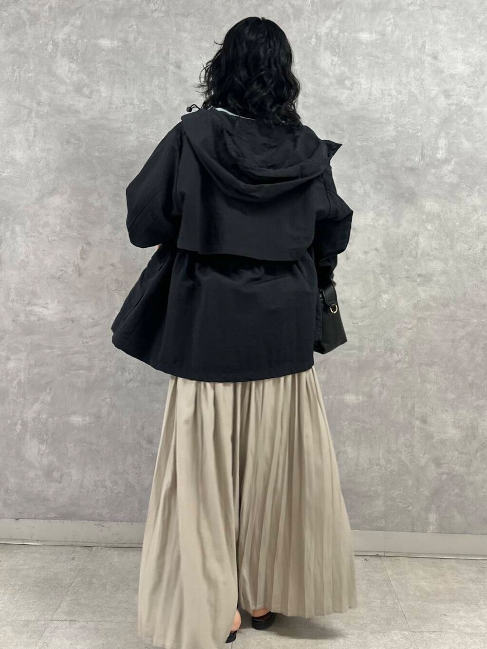 ブラック系のマウンテンパーカー、ブルー系のニット/セーター、ブラック系のショルダーバッグを着用したレディースの春コーディネートの4枚目の写真