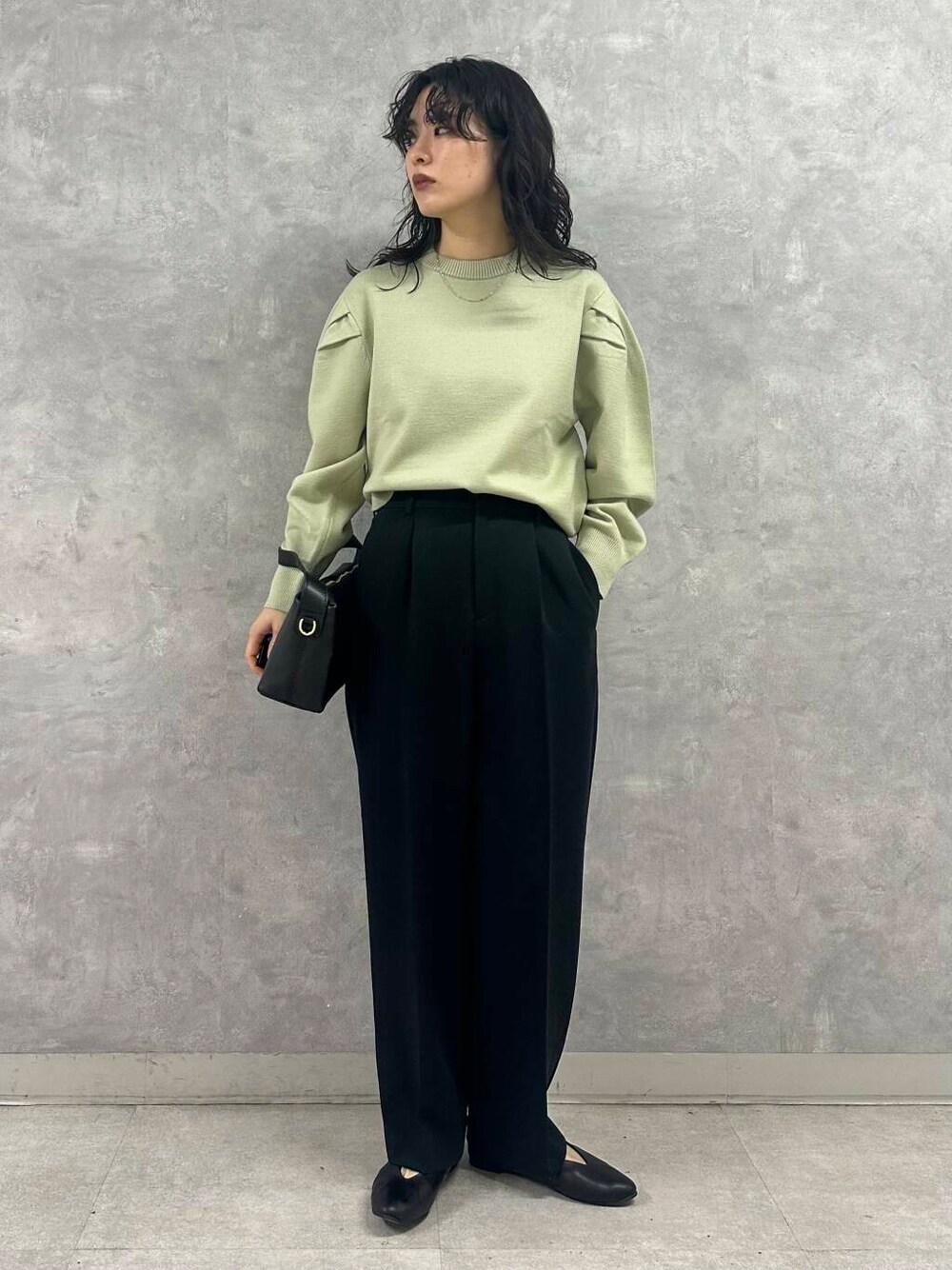 グリーン系のニット/セーター、ブラック系のパンプス、グレー系のダウンジャケット/コートを着用したレディースの冬コーディネートの2枚目の写真