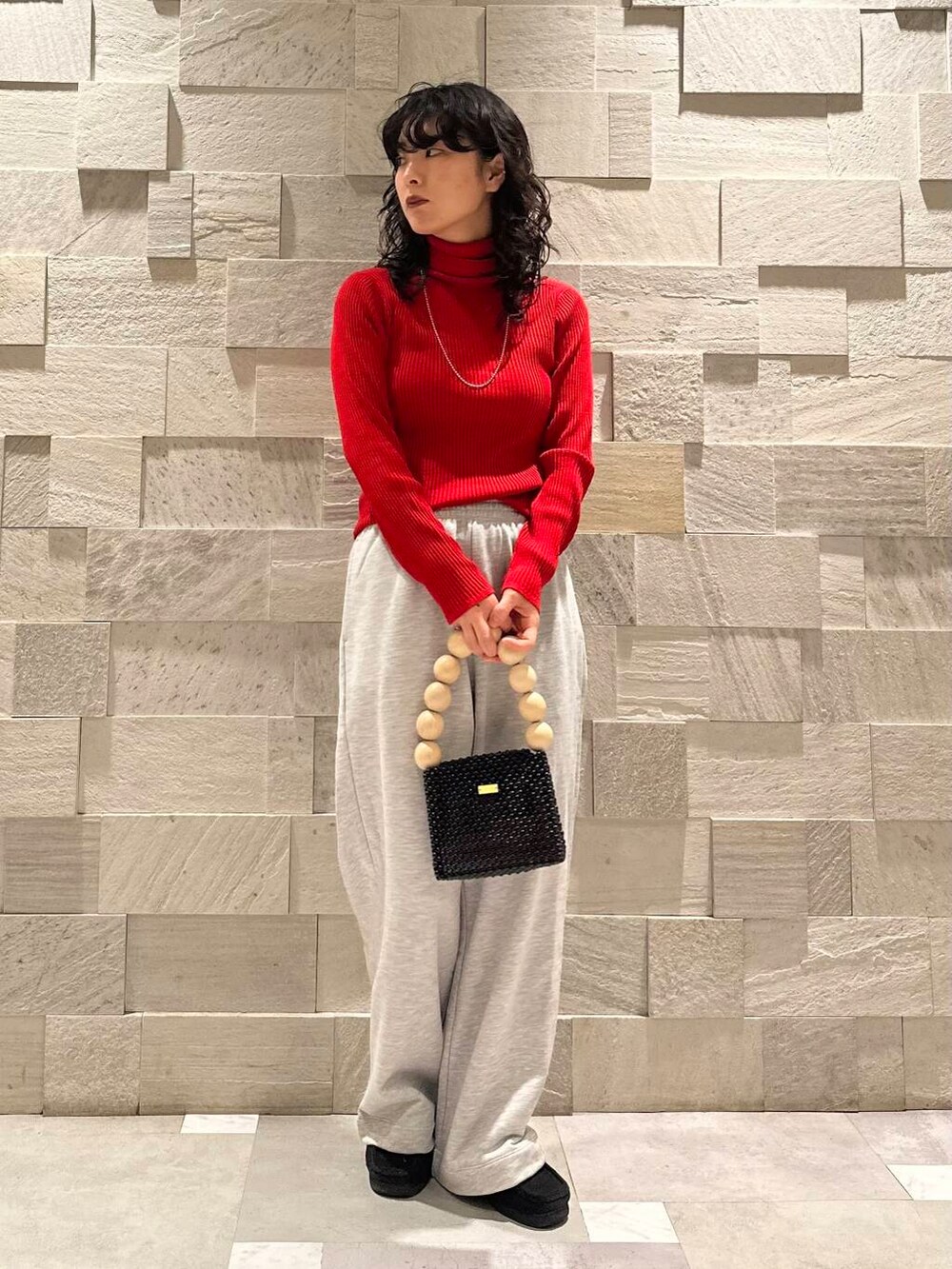 レッド系のニット/セーター、グレー系のその他パンツ、ブラック系のダウンジャケット/コートを着用したレディースの冬コーディネートの6枚目の写真