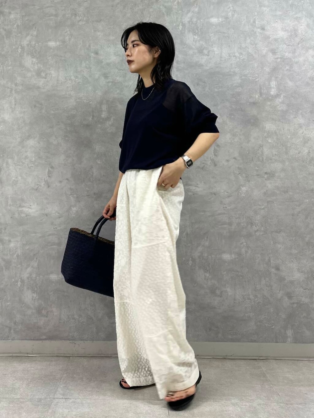 ブルー系のトートバッグ、ブラック系のサンダル、ブラック系のニット/セーターを着用したレディースの夏コーディネートの4枚目の写真