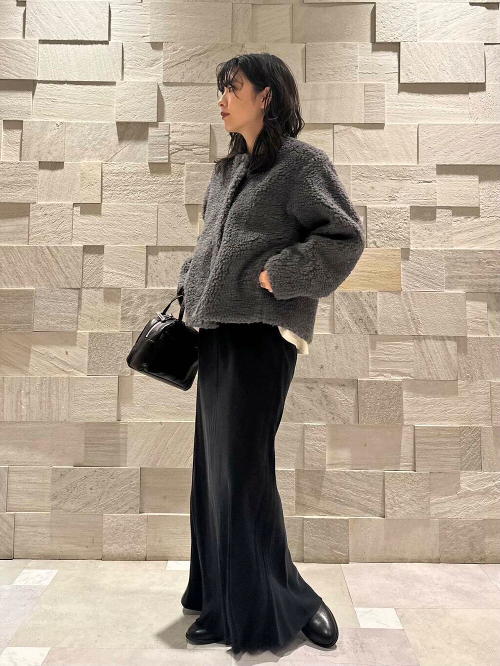 ブラック系のブーツ、ブラック系のショルダーバッグ、ブラック系のスカートを着用したレディースの冬コーディネートの3枚目の写真