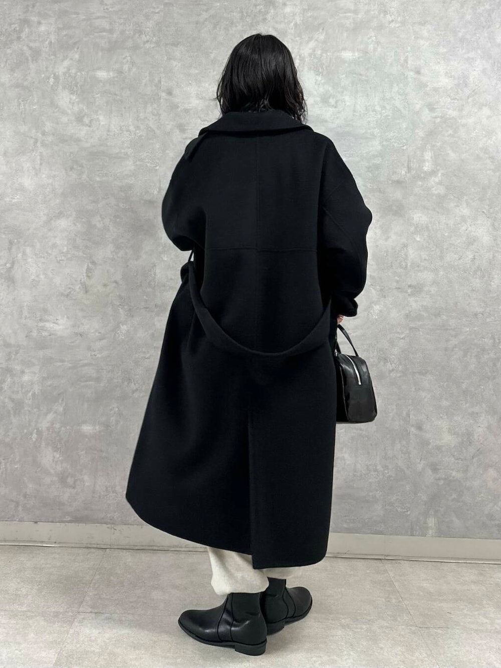 ブラック系のショルダーバッグ、ブラック系のブーツ、ホワイト系のTシャツ/カットソーを着用したレディースの冬コーディネートの3枚目の写真