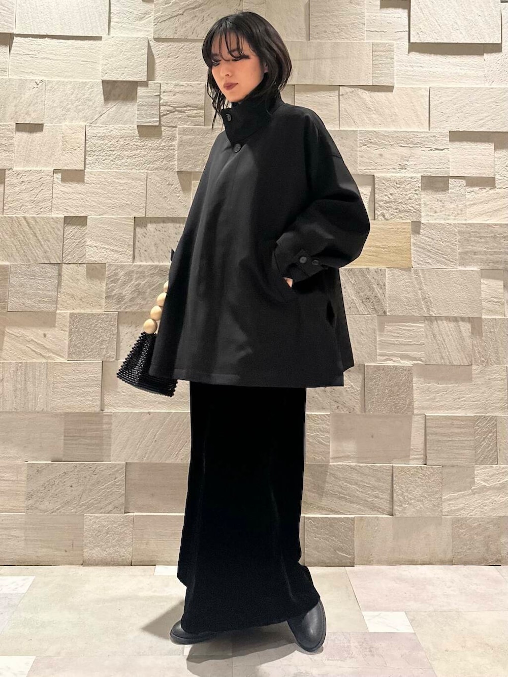 ブラック系のその他アウター、ブラック系のスカート、グレー系のカーディガン/ボレロを着用したレディースの冬コーディネートの2枚目の写真