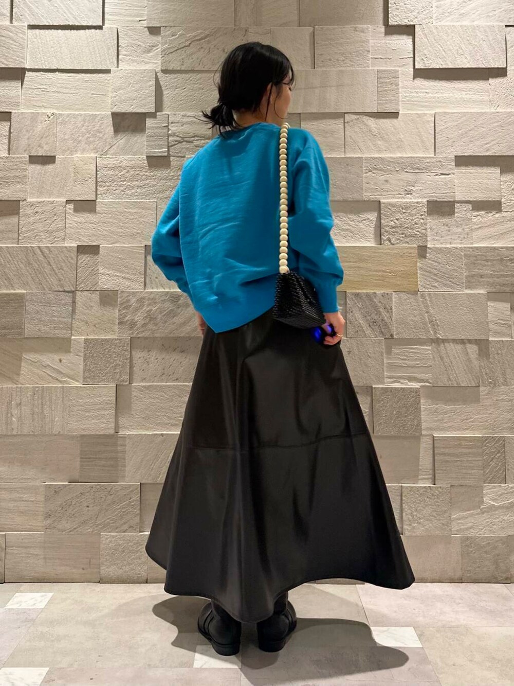 ブルー系のスウェット、ブラック系のブーツ、ブラック系のスカートを着用したレディースの秋コーディネートの4枚目の写真