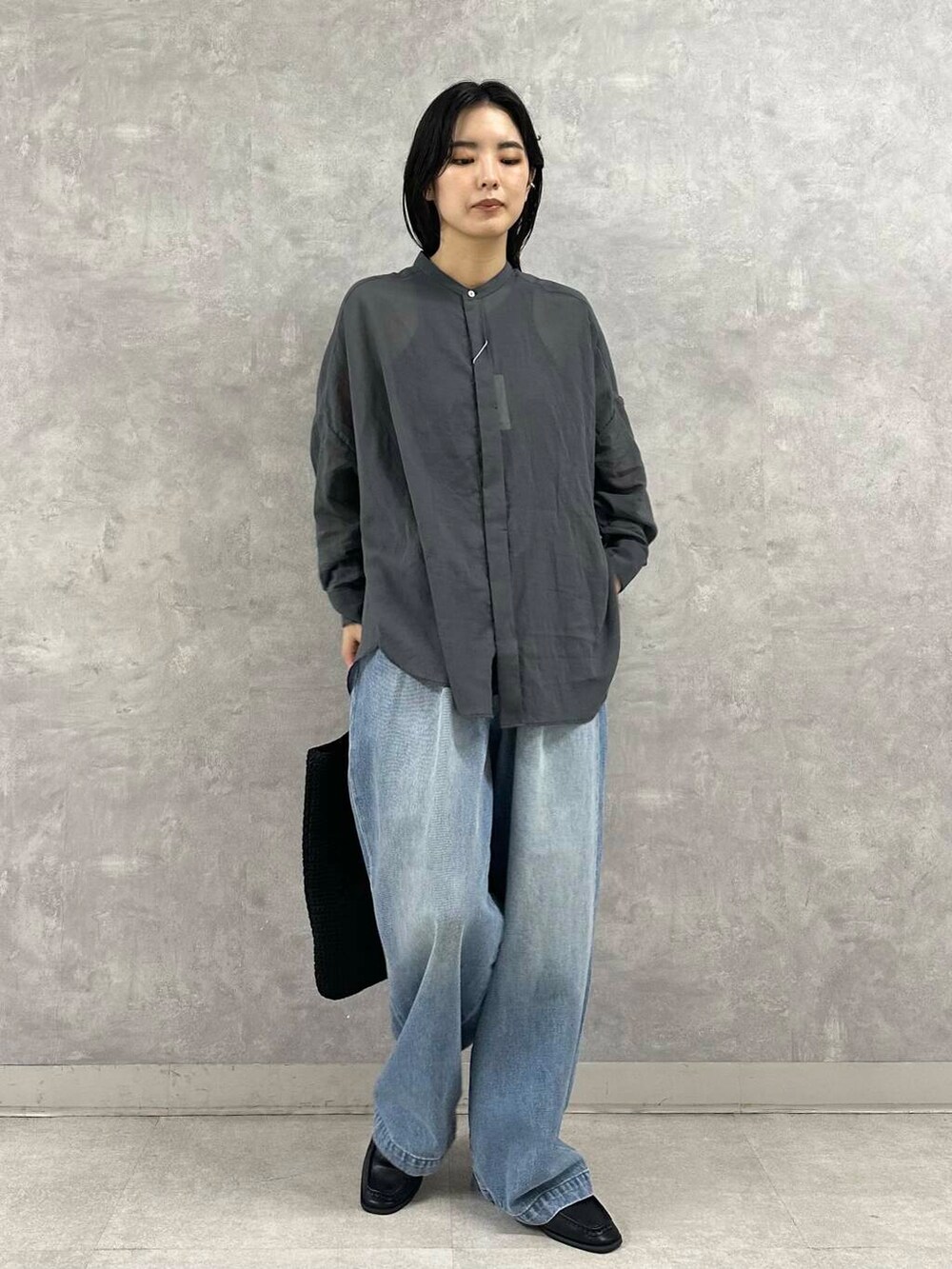 ブラック系のサンダル、ブルー系のデニムパンツ、ブラック系のトートバッグを着用したレディースの夏コーディネートの2枚目の写真