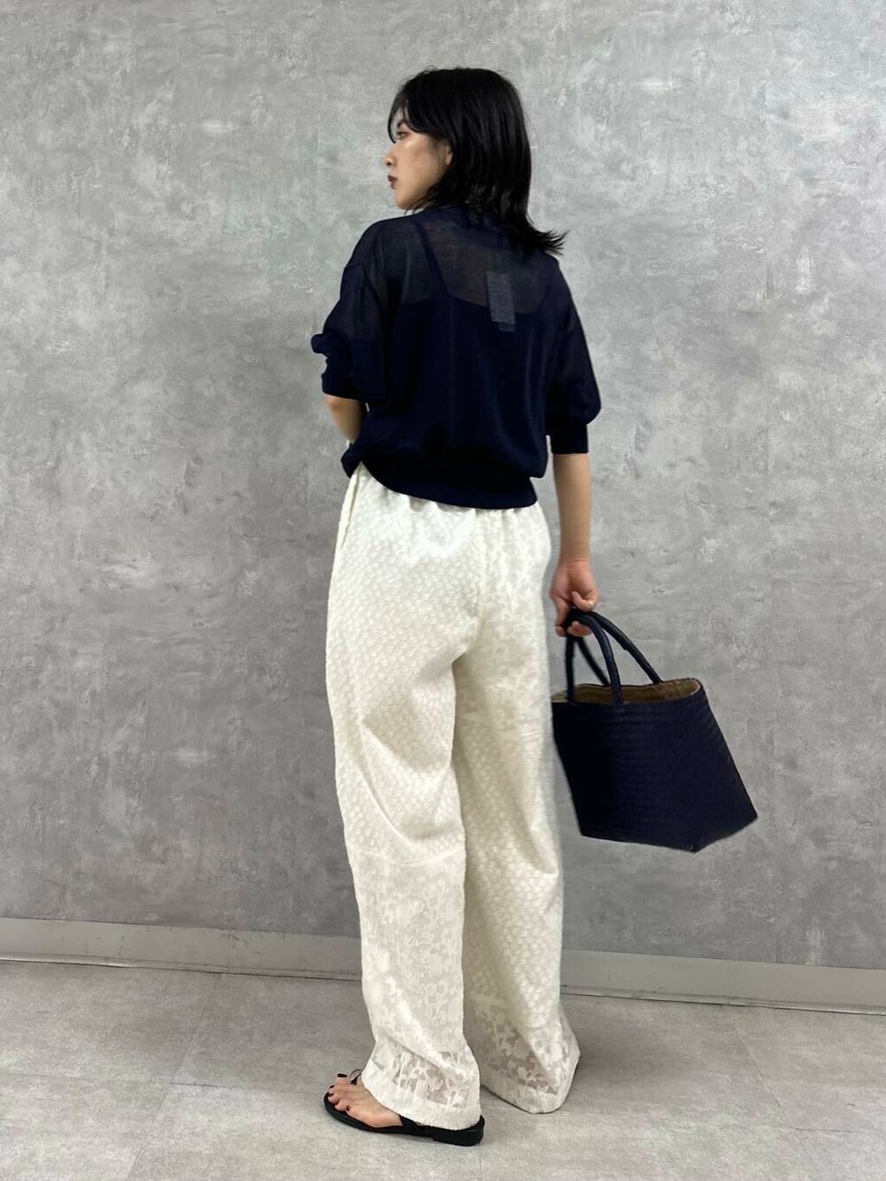 ブルー系のトートバッグ、ブラック系のサンダル、ブラック系のニット/セーターを着用したレディースの夏コーディネートの3枚目の写真