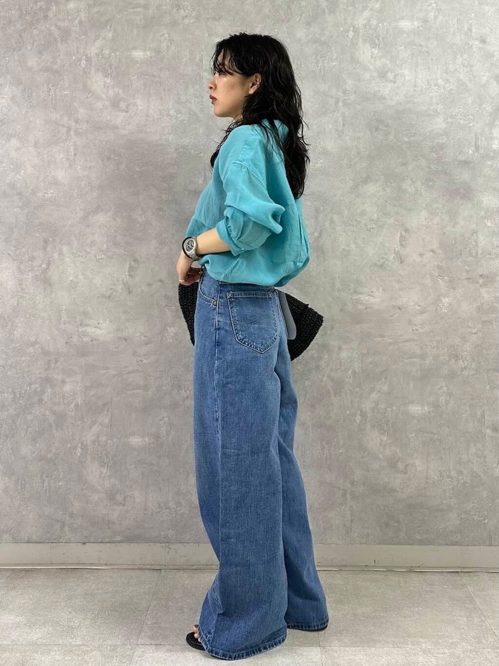 ブラック系のトートバッグ、ブルー系のデニムパンツ、ブラック系のサンダルを着用したレディースの夏コーディネートの3枚目の写真