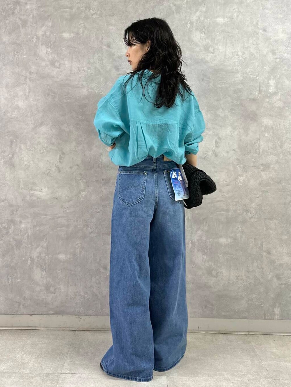 ブラック系のトートバッグ、ブルー系のデニムパンツ、ブラック系のサンダルを着用したレディースの夏コーディネートの4枚目の写真