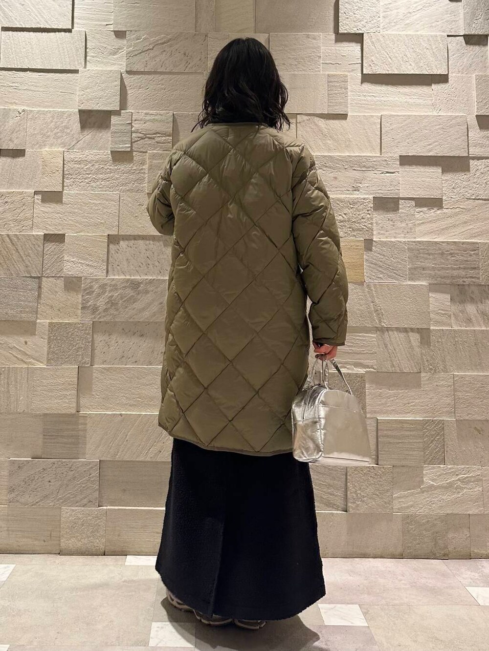 グリーン系のダウンジャケット/コート、ブラック系のスウェット、シルバー系のショルダーバッグを着用したレディースの秋コーディネートの4枚目の写真