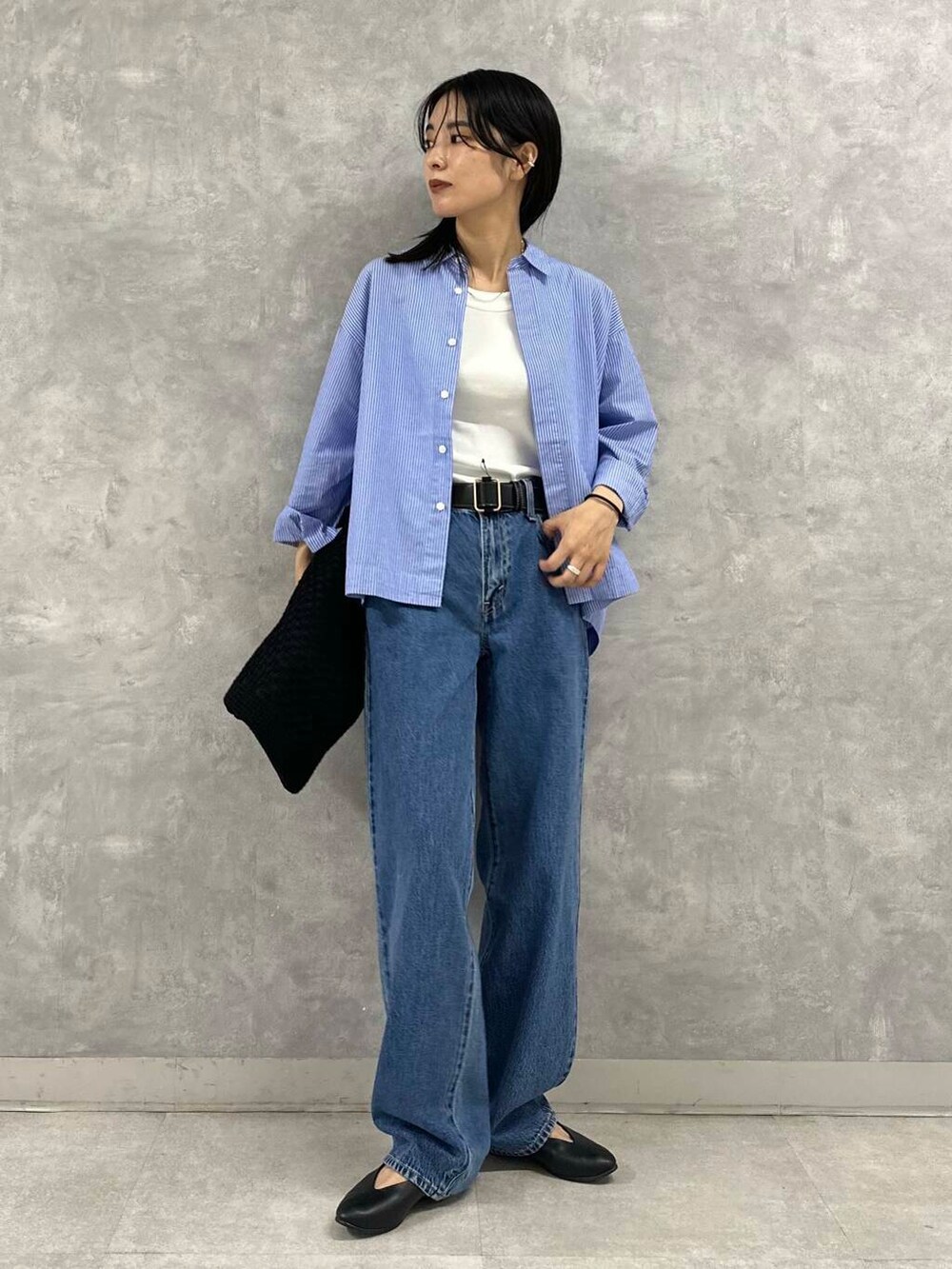 ホワイト系のタンクトップ、ブルー系のデニムパンツ、ブラック系のトートバッグを着用したレディースの夏コーディネートの2枚目の写真