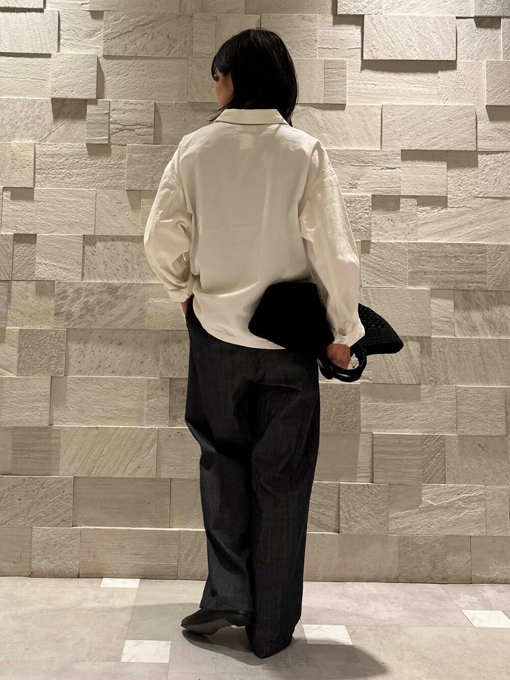 ブラック系のトートバッグ、ブラック系のパンプス、ブルー系のデニムパンツを着用したレディースの秋コーディネートの3枚目の写真