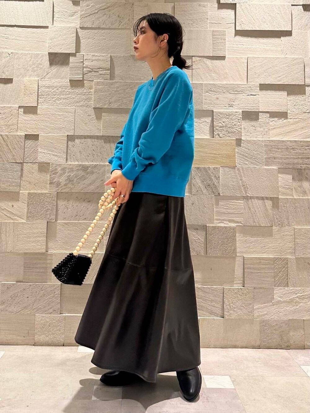 ブルー系のスウェット、ブラック系のブーツ、ブラック系のスカートを着用したレディースの秋コーディネートの3枚目の写真