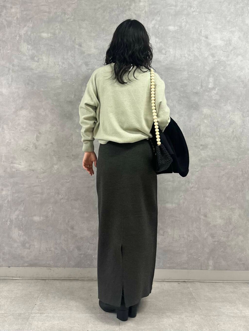 ブラック系のその他アウター、グレー系のスカート、グリーン系のニット/セーターを着用したレディースの冬コーディネートの5枚目の写真