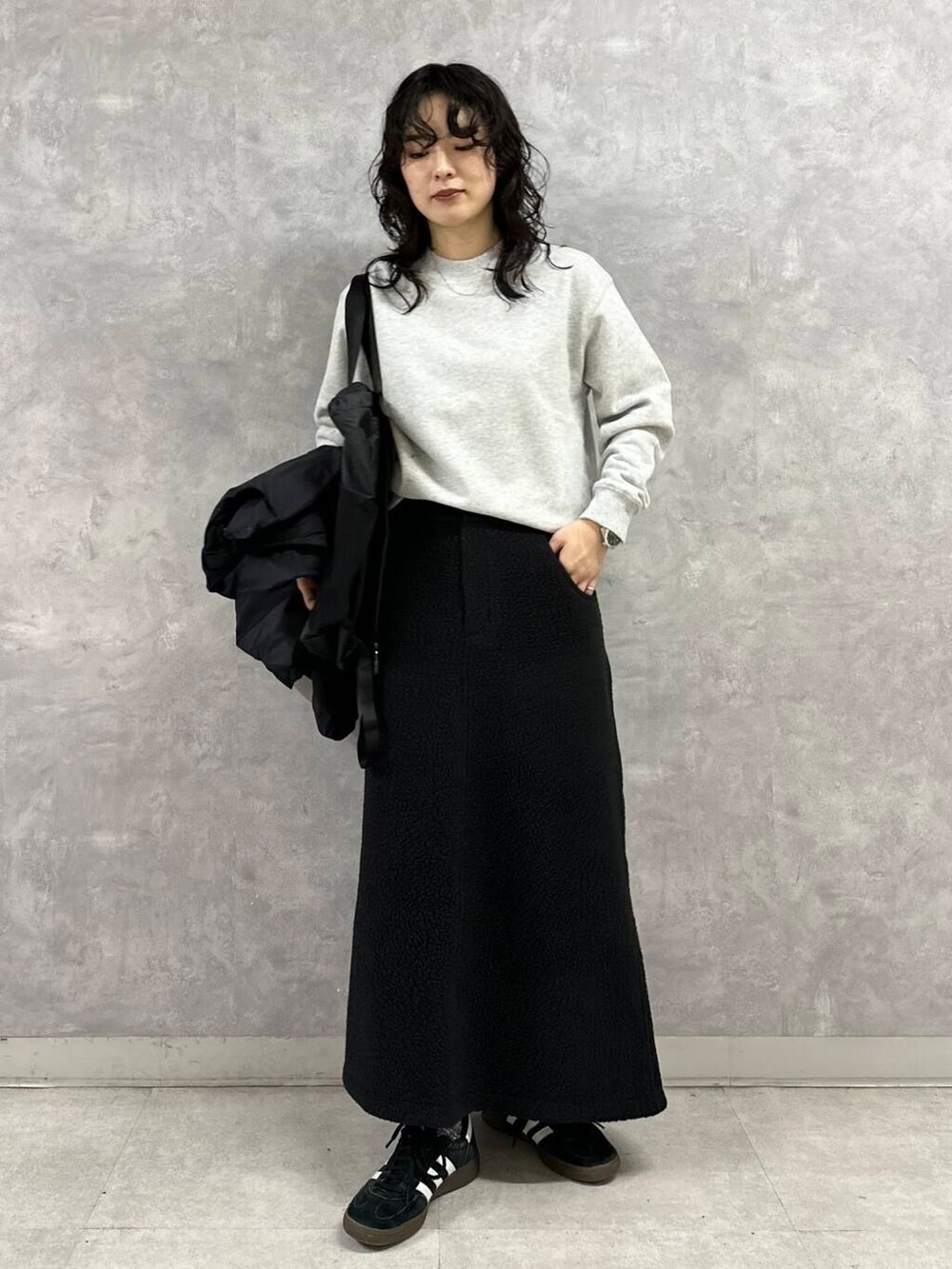 ブラック系のダウンジャケット/コート、グレー系のTシャツ/カットソー、ブラック系のスカートを着用したレディースの冬コーディネートの2枚目の写真