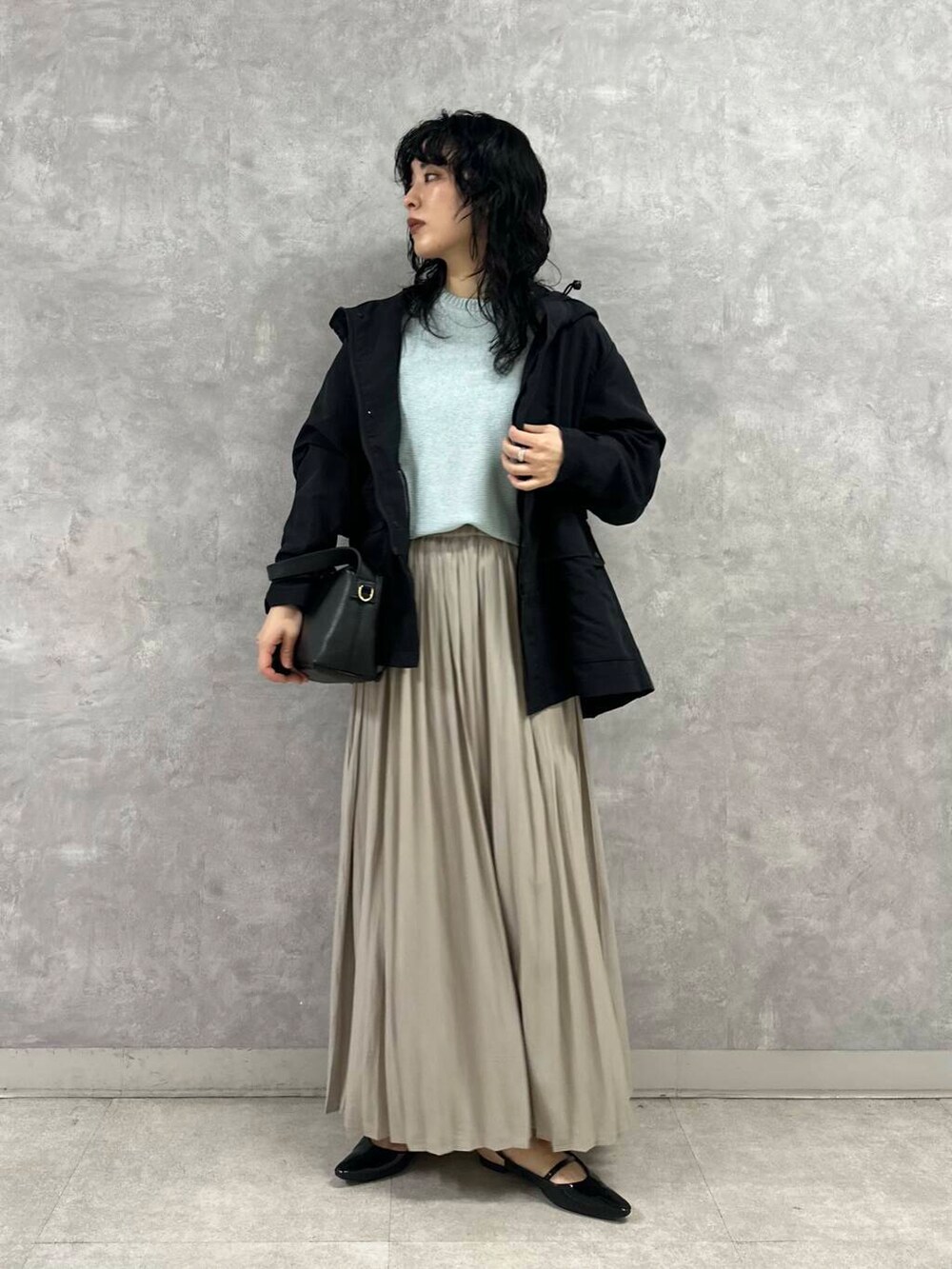 ブラック系のマウンテンパーカー、ブルー系のニット/セーター、ブラック系のショルダーバッグを着用したレディースの春コーディネートの5枚目の写真