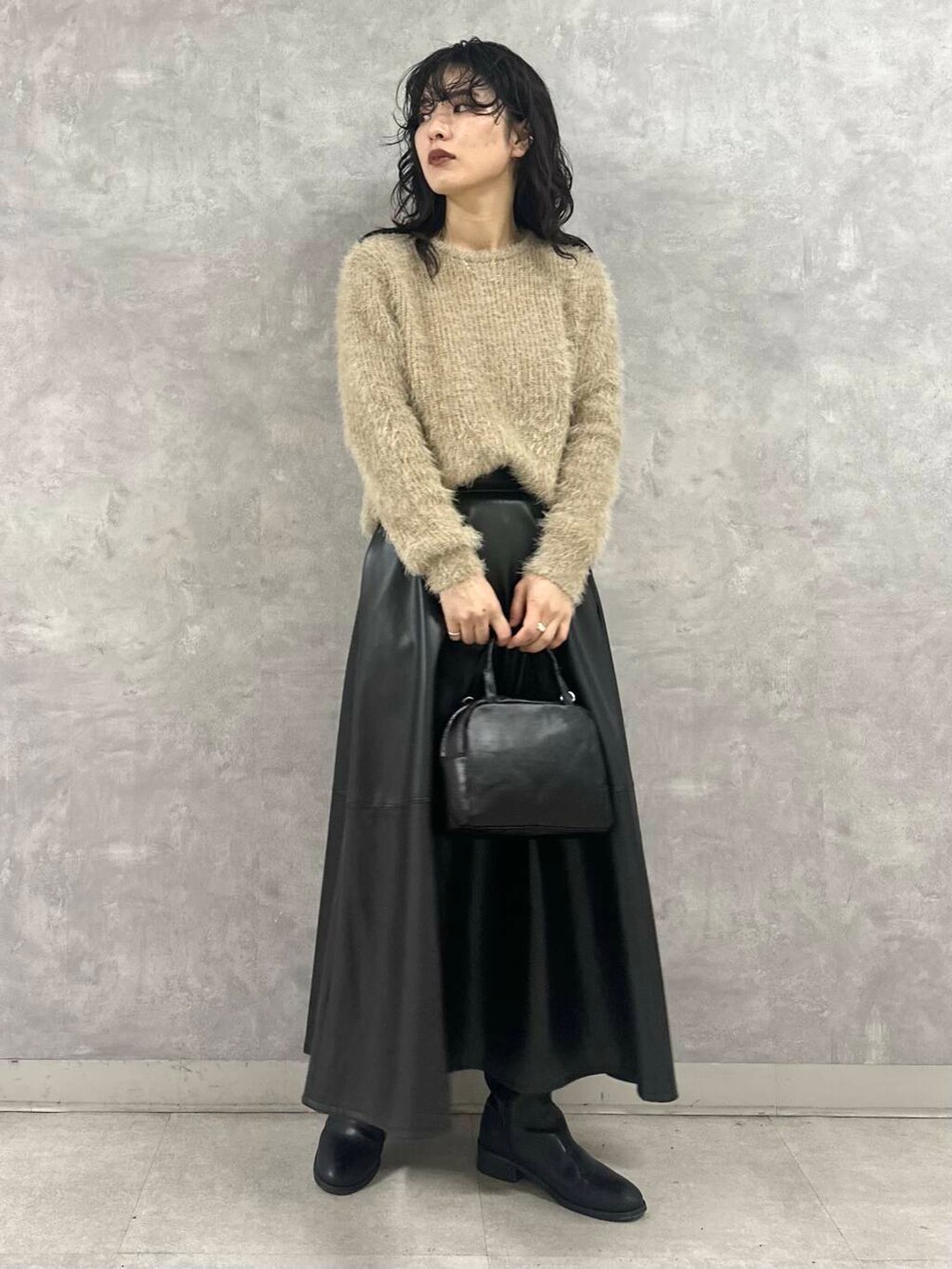 ブラック系のその他アウター、ブラック系のショルダーバッグ、ブラック系のスカートを着用したレディースの冬コーディネートの2枚目の写真