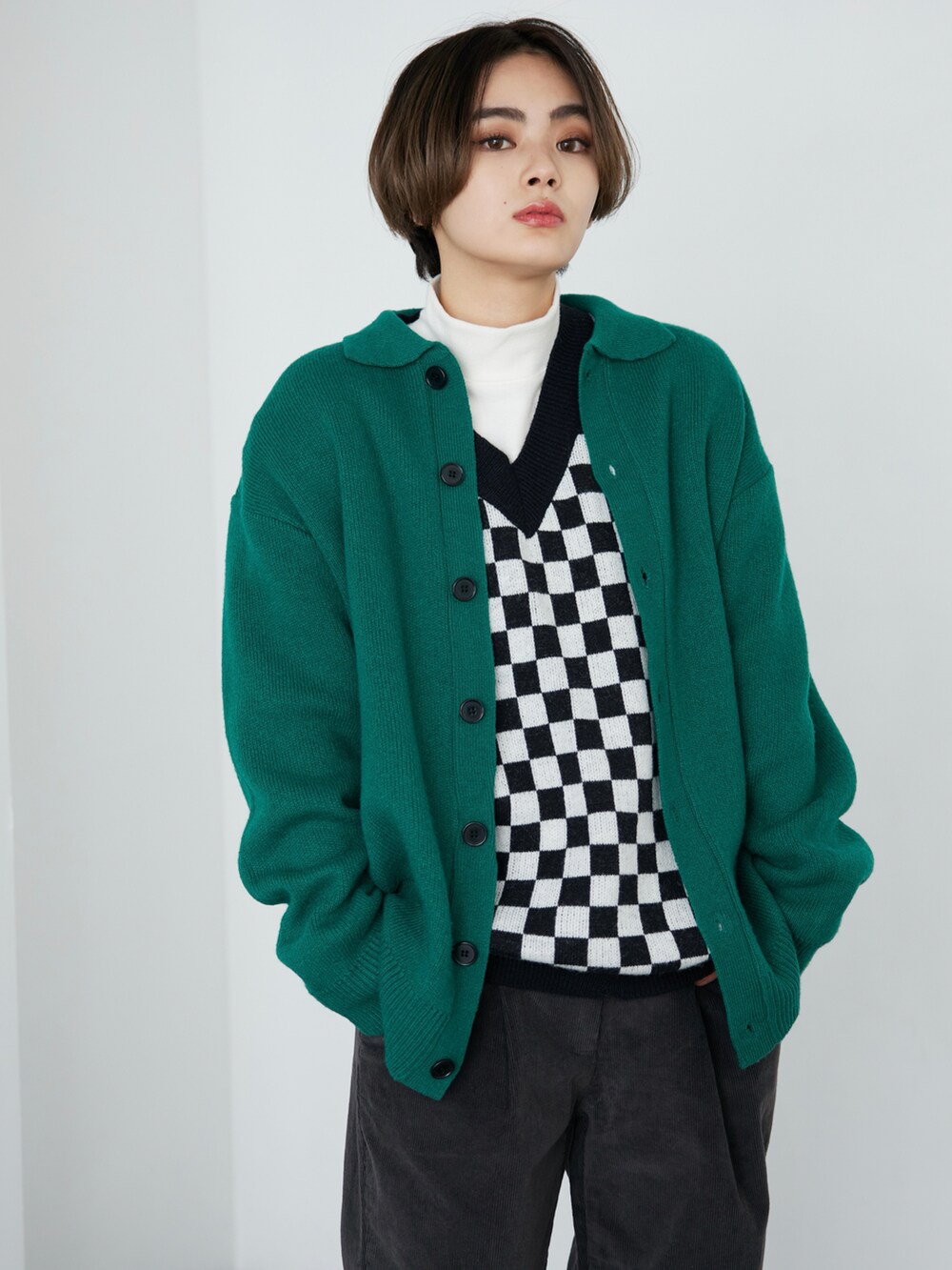 グリーン系のカーディガン/ボレロ、ブラック系のベスト、ブラック系のパンツを着用したレディースの冬コーディネートの2枚目の写真