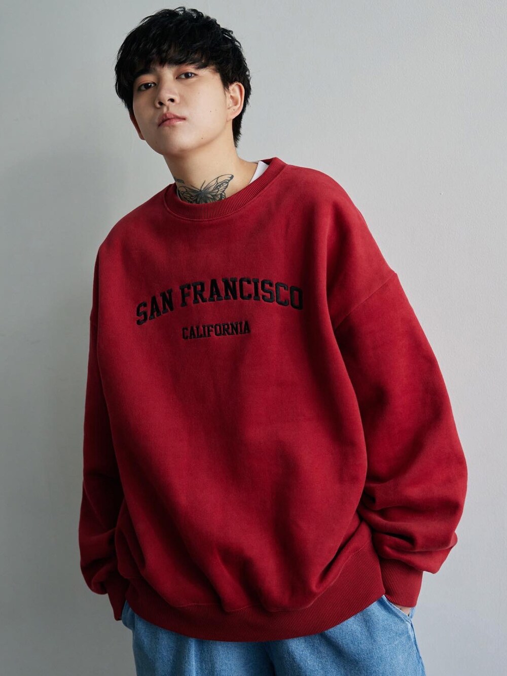 レッド系のスウェット、その他のデニムパンツ、ブラック系のスニーカーを着用したレディースの冬コーディネートの2枚目の写真