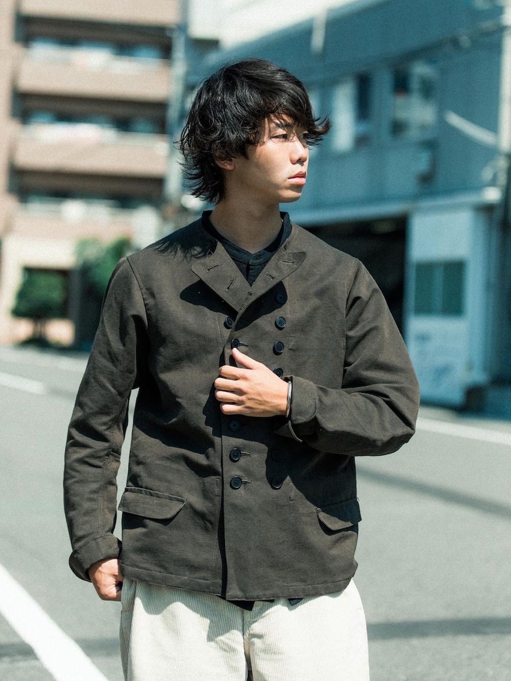 グリーン系のノーカラージャケット、ホワイト系のカーゴパンツ、ブラウン系のスリッポンを着用したメンズの秋コーディネートの2枚目の写真