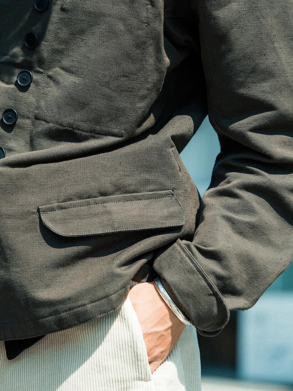 グリーン系のノーカラージャケット、ホワイト系のカーゴパンツ、ブラウン系のスリッポンを着用したメンズの秋コーディネートの4枚目の写真