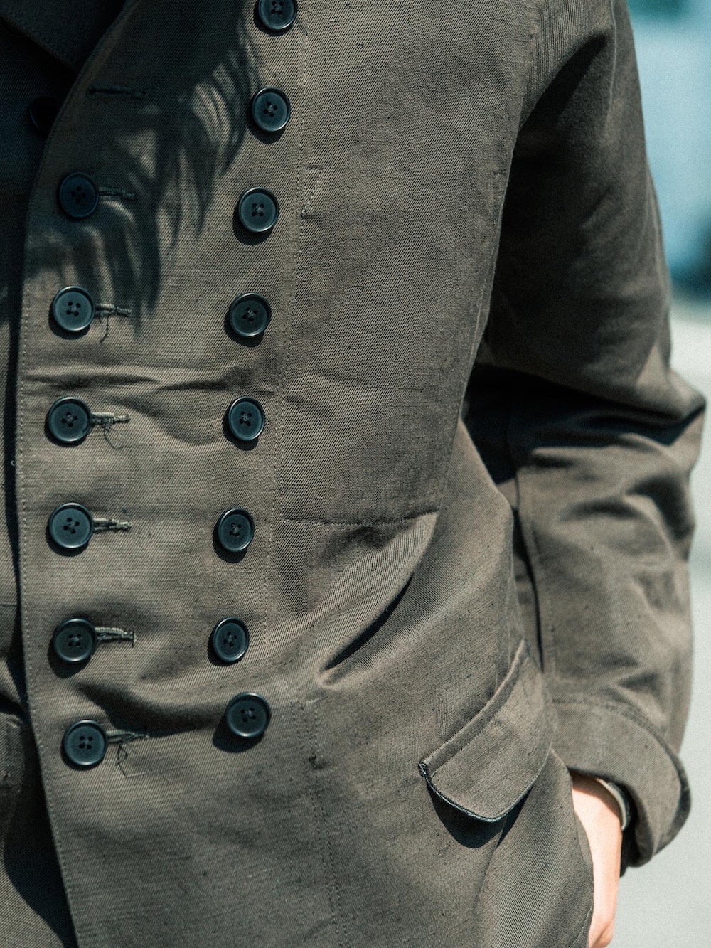 グリーン系のノーカラージャケット、ホワイト系のカーゴパンツ、ブラウン系のスリッポンを着用したメンズの秋コーディネートの5枚目の写真