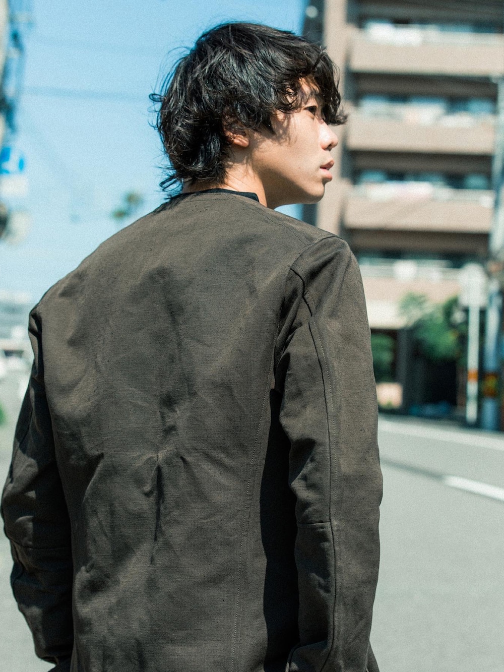 グリーン系のノーカラージャケット、ホワイト系のカーゴパンツ、ブラウン系のスリッポンを着用したメンズの秋コーディネートの3枚目の写真