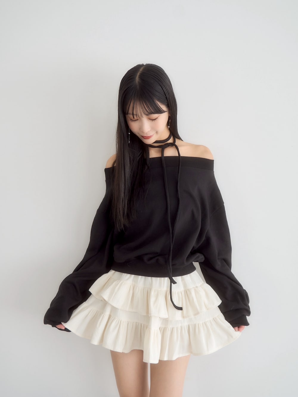 ブラック系のスウェット、ホワイト系のスカート、ブラック系のダウンジャケット/コートを着用したレディースの冬コーディネートの2枚目の写真