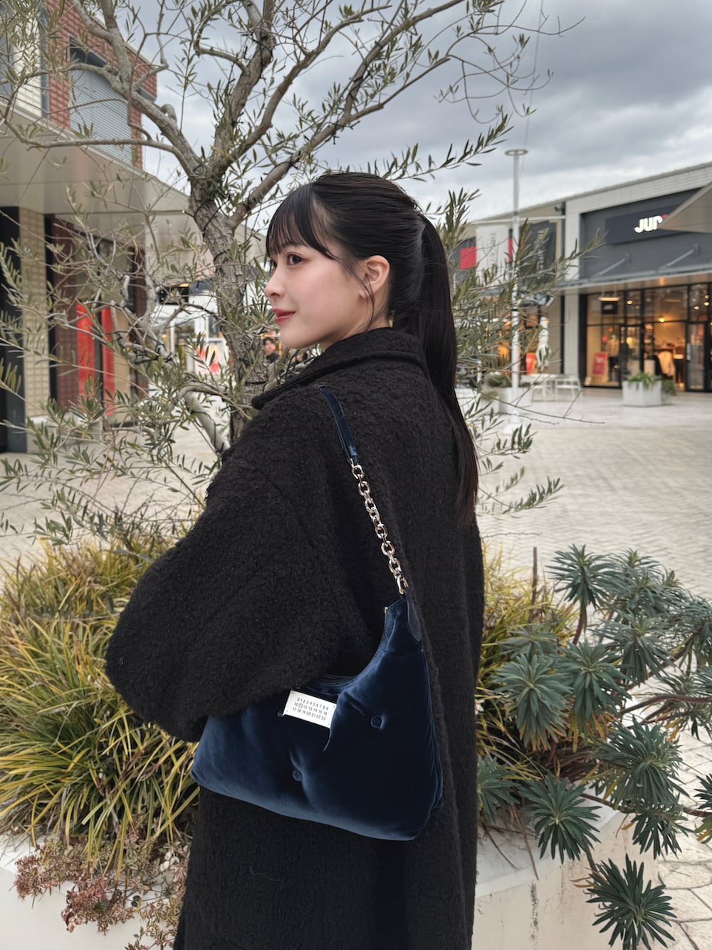 ブルー系のバッグ、ブルー系のデニムパンツ、ブラック系のブーツを着用したレディースの冬コーディネートの2枚目の写真