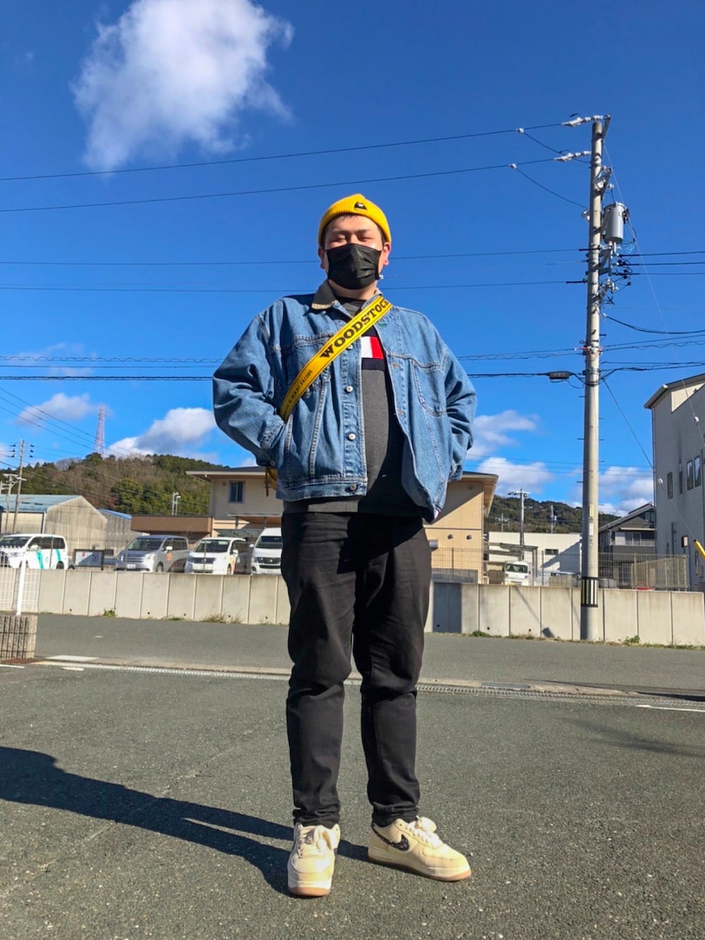 イエロー系のショルダーバッグ、ブルー系のデニムジャケット、ホワイト系のスニーカーを着用したメンズの冬コーディネートの2枚目の写真