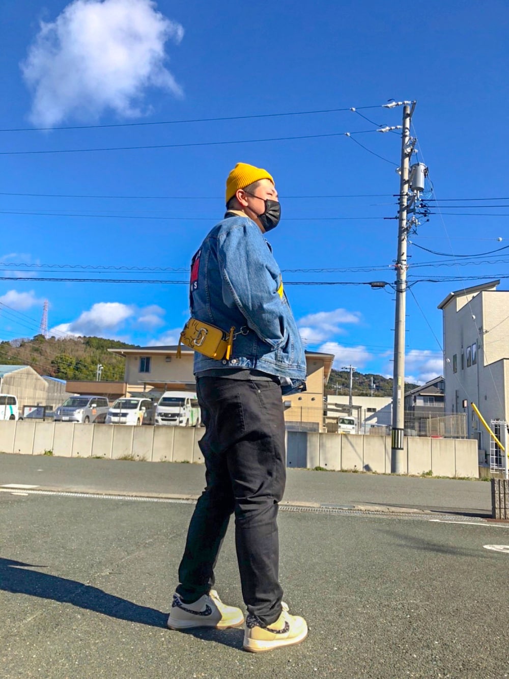 イエロー系のショルダーバッグ、ブルー系のデニムジャケット、ホワイト系のスニーカーを着用したメンズの冬コーディネートの3枚目の写真