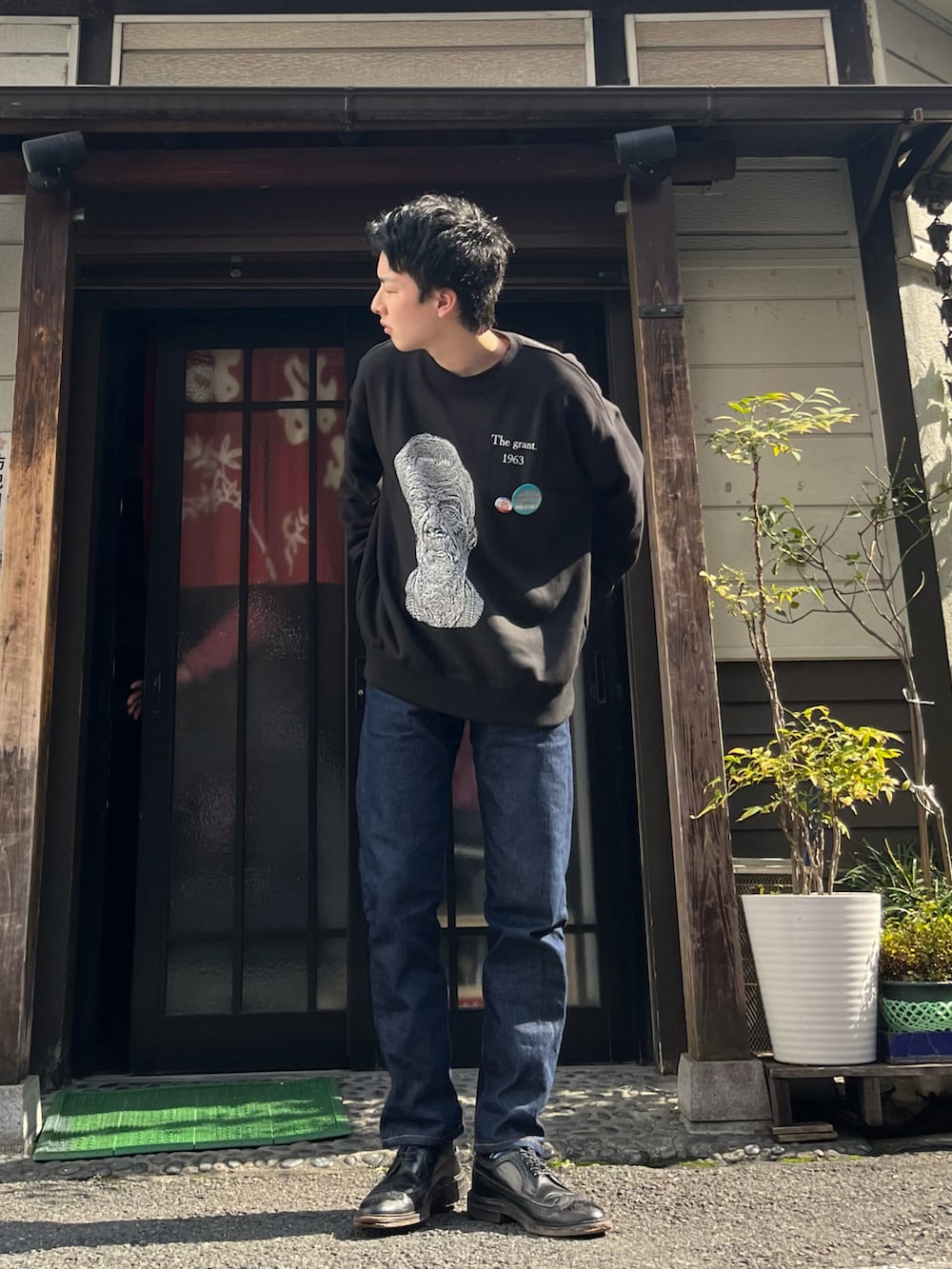 ブルー系のデニムパンツ、ブラック系のドレスシューズ、ブラック系のスウェットを着用したメンズの春コーディネートの2枚目の写真