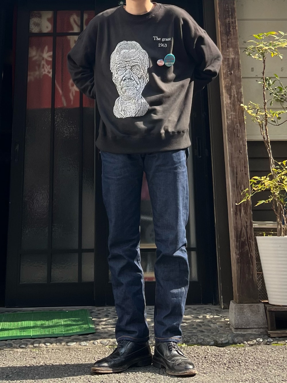 ブルー系のデニムパンツ、ブラック系のドレスシューズ、ブラック系のスウェットを着用したメンズの春コーディネートの3枚目の写真