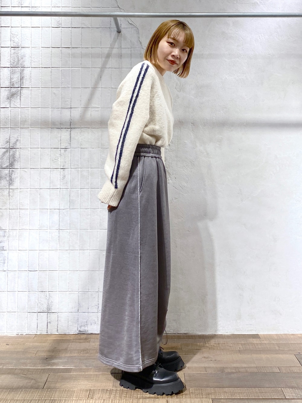 ホワイト系のニット/セーター、グレー系のスカート、ブラック系のブーツを着用したレディースの冬コーディネートの2枚目の写真