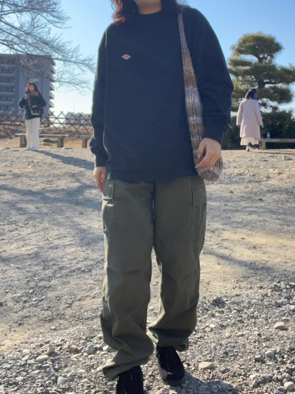 グリーン系のカーゴパンツ、ブラック系のブーツ、ブラック系のTシャツ/カットソーを着用したレディースの冬コーディネートの2枚目の写真