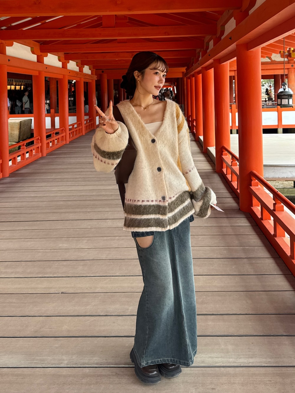 ホワイト系のカーディガン/ボレロ、ブラウン系のショルダーバッグ、ブルー系のデニムスカートを着用したレディースの秋コーディネートの5枚目の写真