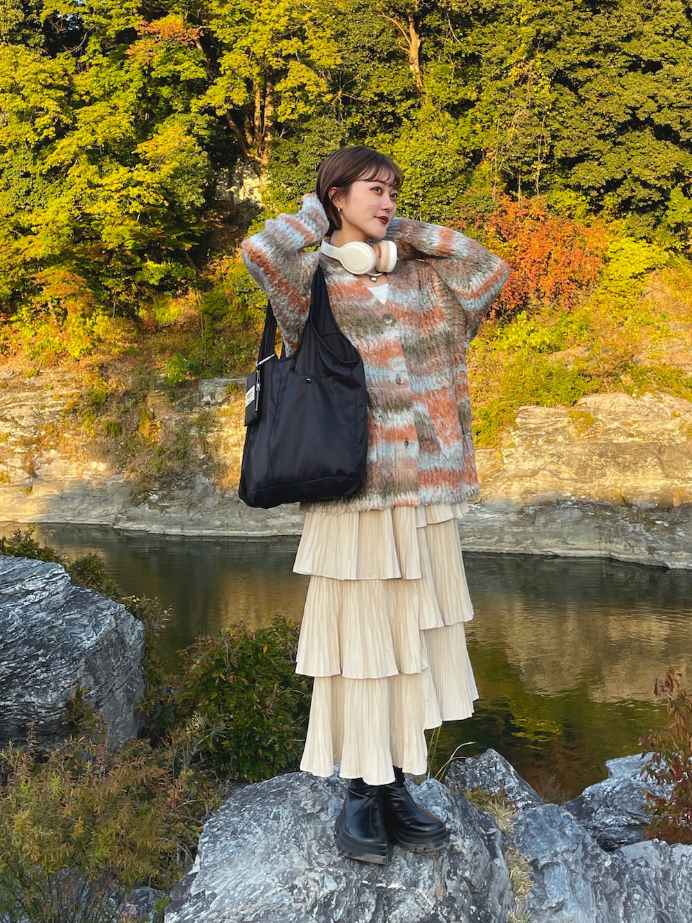 オレンジ系のカーディガン/ボレロ、ブラック系のブーツを着用したレディースの春コーディネートの5枚目の写真