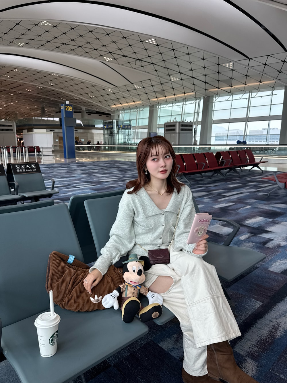 ホワイト系のカーディガン/ボレロ、ホワイト系のデニムパンツ、ブラウン系のブーツを着用したレディースの冬コーディネートの4枚目の写真